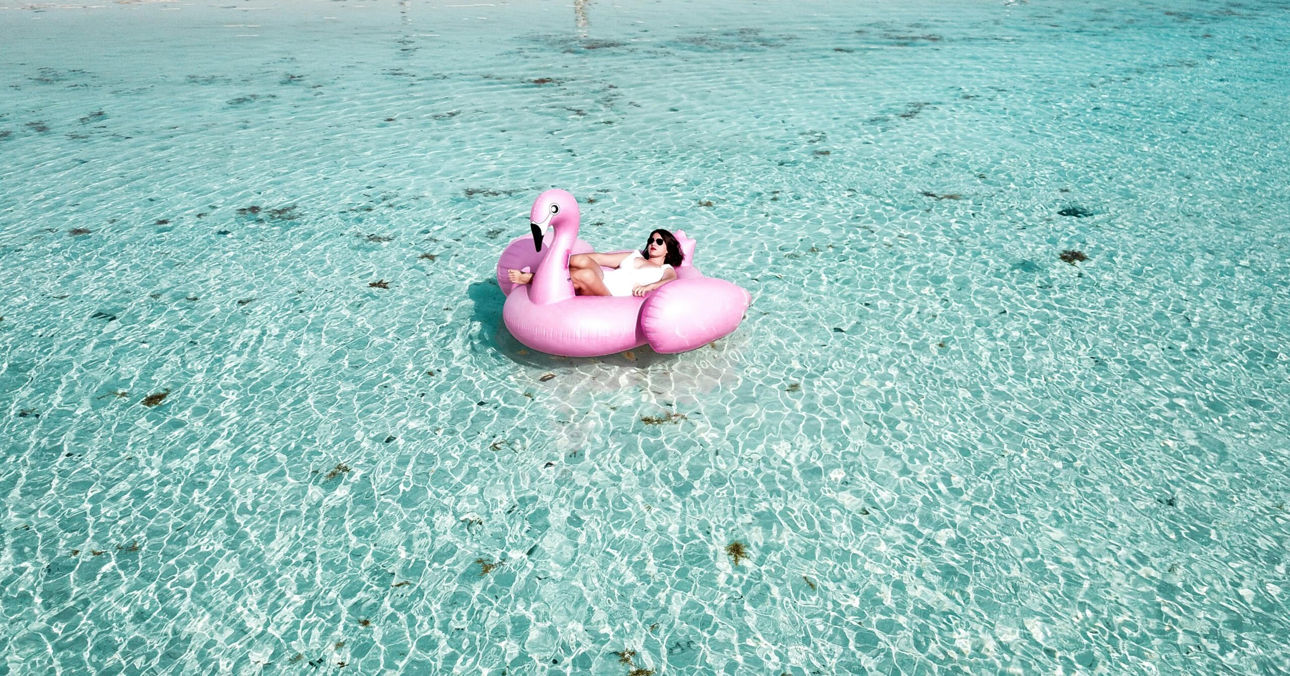 A woman enjoying leisure time on a flamingo float in the clear waters of Isla Mujeres.